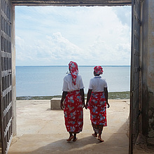 Zwei Frauen in afrikanischer Tracht vor einem Ufer
